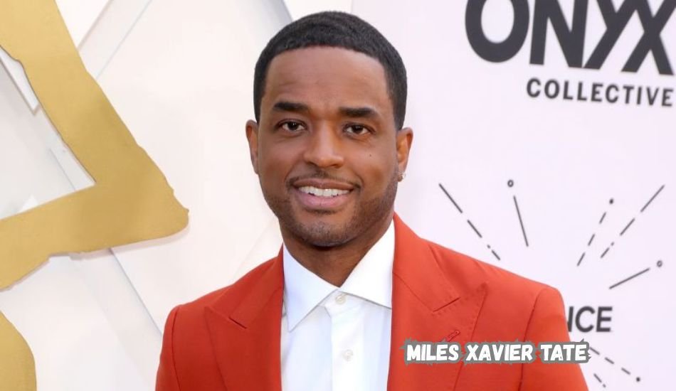 Miles Xavier Tate smiling at a public event in a navy suit